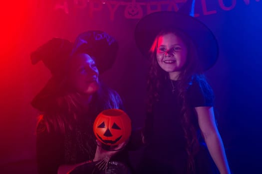 Funny child girl and woman in witches costumes for Halloween with pumpkin Jack and dog