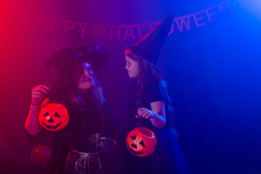 Funny child girl and woman in witches costumes for Halloween with pumpkin Jack and dog