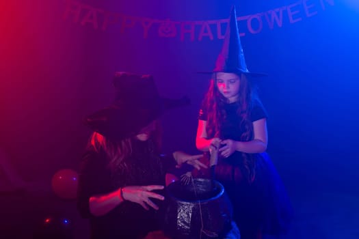 Funny child girl and woman in witches costumes for Halloween with pumpkin Jack and dog