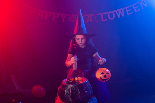 Little witch child cooking potion in the cauldron on Halloween