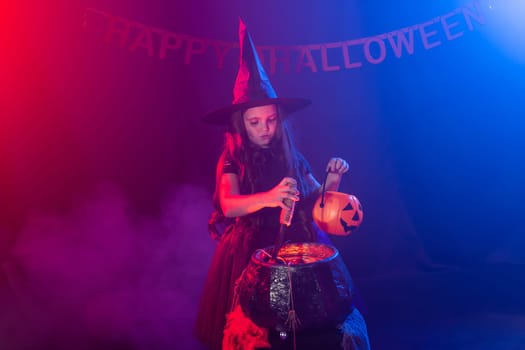 Little witch child cooking potion in the cauldron on Halloween