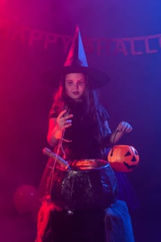 Little witch child cooking potion in the cauldron on Halloween