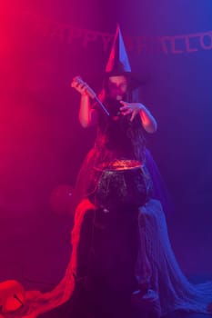 Little witch child cooking potion in the cauldron on Halloween