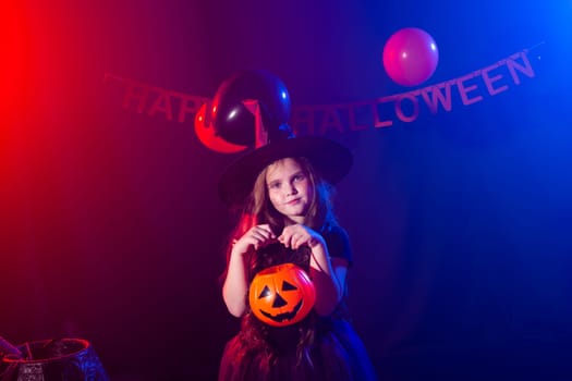 Funny child girl in witch costume for Halloween with pumpkin Jack