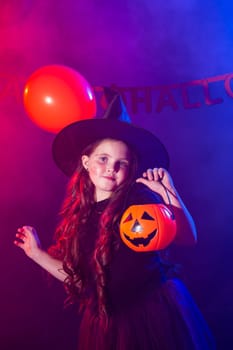 Funny child girl in witch costume for Halloween with pumpkin Jack