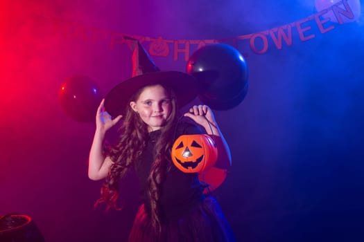 Funny child girl in witch costume for Halloween with pumpkin Jack