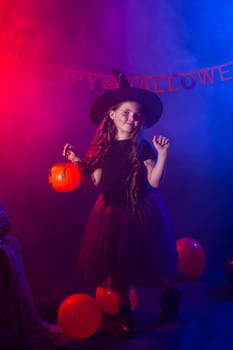 Funny child girl in witch costume for Halloween with pumpkin Jack