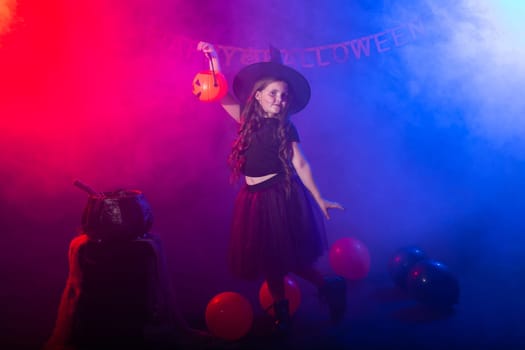 Funny child girl in witch costume for Halloween with pumpkin Jack