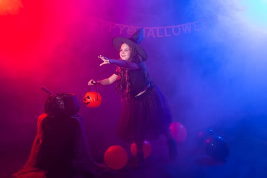 Funny child girl in witch costume for Halloween with pumpkin Jack