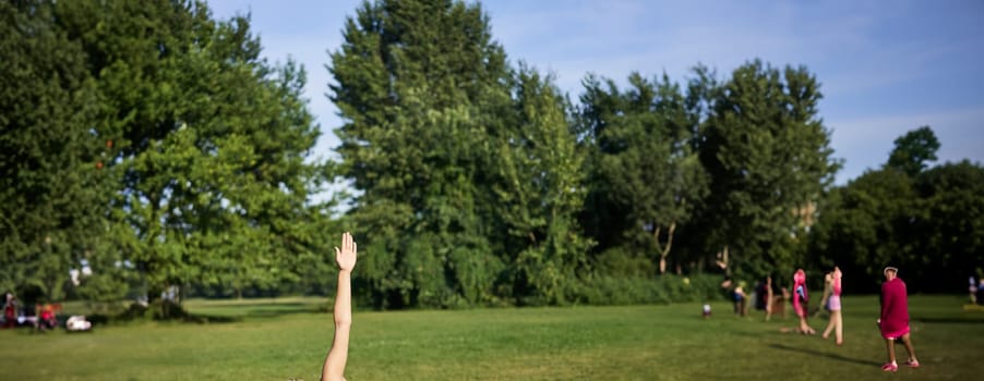 Vertical shot of young korean woman doing yoga training on rubber mat, making asana exercises on fresh air in park.