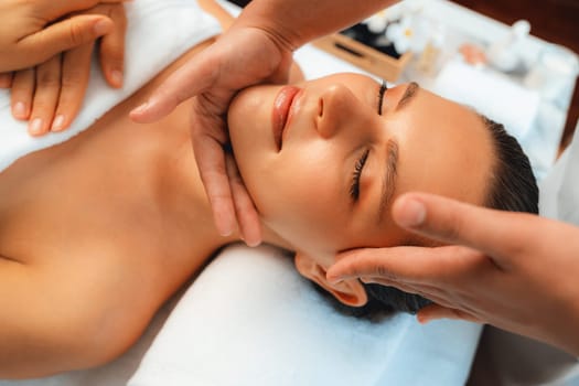 Caucasian woman enjoying relaxing anti-stress head massage and pampering facial beauty skin recreation leisure in dayspa modern light ambient at luxury resort or hotel spa salon. Quiescent