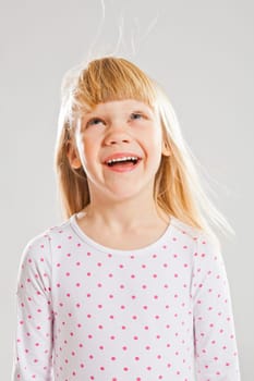 Studio portrait of happy smiling young girl looking up with wind blowing her hair