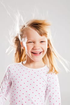 Studio portrait of happy smiling young girl with wind blowing her hair