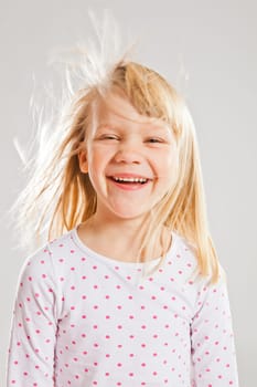 Studio portrait of happy smiling young girl with wind blowing her hair