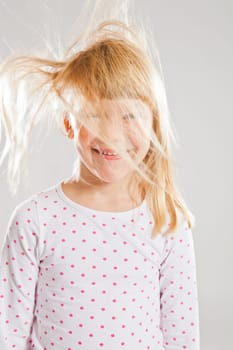 Studio portrait of happy smiling young girl with wind blowing her hair