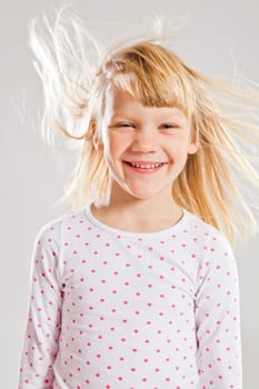 Studio portrait of happy smiling young girl with wind blowing her hair