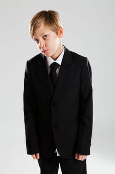 Studio portrait of serious looking young boy wearing black suit