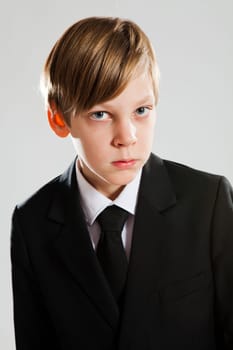 Studio portrait of serious looking young boy wearing black suit