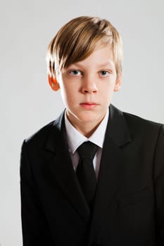 Studio portrait of serious looking young boy wearing black suit
