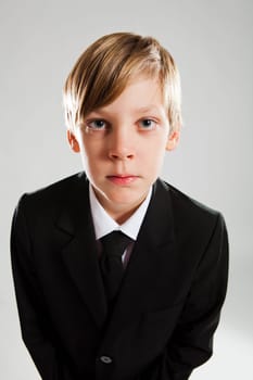 Studio portrait of serious looking young boy wearing black suit