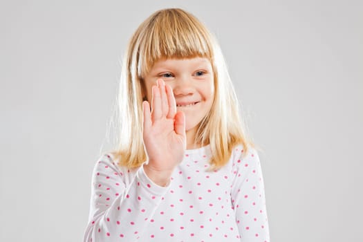 Studio portrait of happy smiling young girl using hand as stop signal or waving
