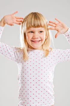Studio portrait of happy smiling young girl looking to the side with raised hands