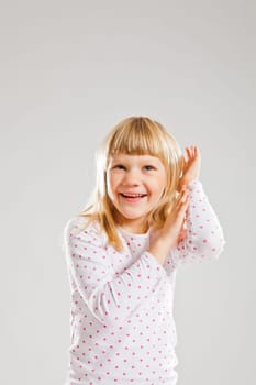 Studio portrait of happy smiling young girl looking upwards with raised hands