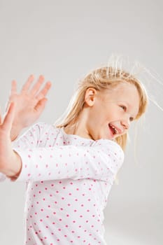 Studio portrait of happy smiling young girl with raised hands looking to the side