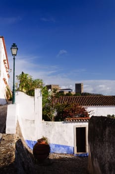 Medieval houses in the ancient city of Obidos, Portugal with castle walls  in the background