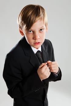 Studio portrait of serious looking young boy wearing black suit