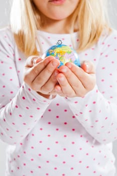 Studio portrait of young girl holding world globe in hands