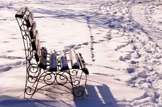 Park Bench In Winter - wood bench in a park covered with snow