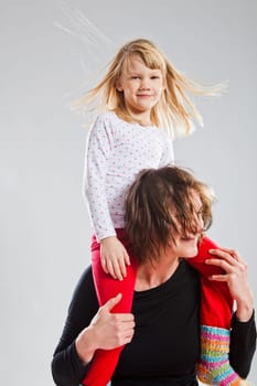 Studio portrait of happy woman carrying smiling young girl on shoulders