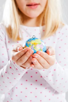 Studio portrait of young girl holding world globe in hands