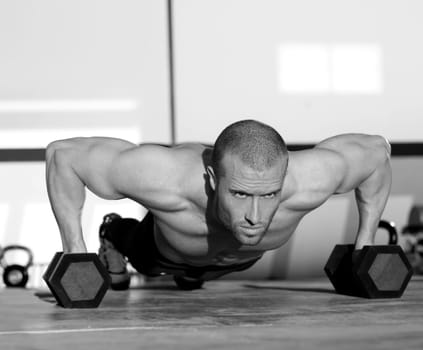 Gym man push-up strength pushup exercise with dumbbell in a crossfit workout