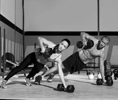 Gym man and woman push-up strength pushup with dumbbell in a crossfit workout