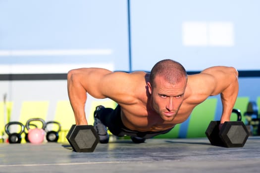 Gym man push-up strength pushup exercise with dumbbell in a crossfit workout