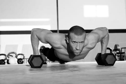 Gym man push-up strength pushup exercise with dumbbell in a crossfit workout