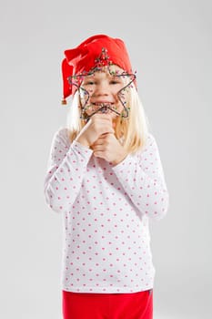 Studio portrait of smiling young girl wearing red Christmas elf hat and holding star decoration
