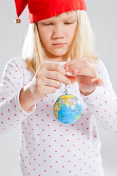 Studio portrait of young girl with red Christmas elf hat holding world globe in hands