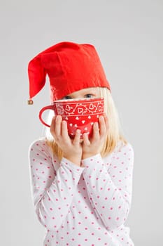 Studio portrait of happy young girl wearing red Christmas elf hat and holding a big red cup