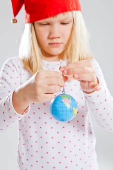Studio portrait of young girl with red Christmas elf hat holding world globe in hands