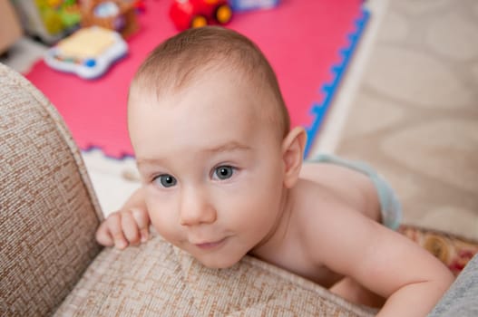 Cute little boy is climbing on sofa