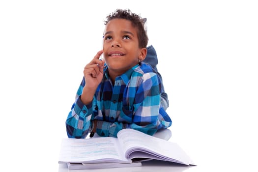 Little african boy lying down on the floor and reading book, isolated on white background
