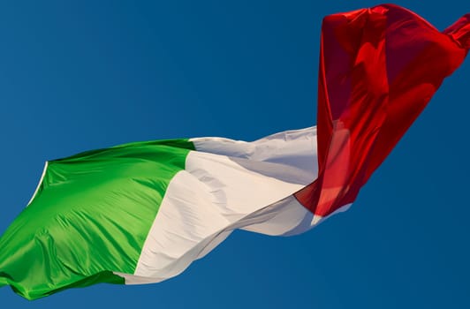A large Italian flag in the blue sky free