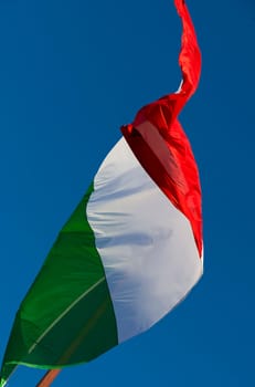 A large Italian flag in the blue sky free