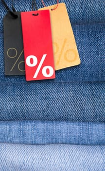 Sale Tags With Percentage Symbol on Stack of Blue Jeans