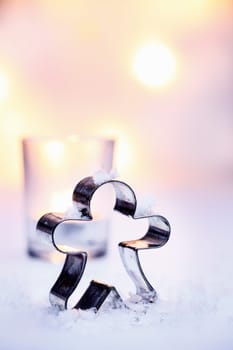 Standing figure cookie cutter Christmas background in snow against a backdrop of soft glowing party lights with copyspace for your seasonal greeting