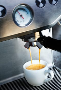 Automatic filter coffee machine dispensing a cup of delicious hot frothy aromatic coffee into a white ceramic cup in a catering and hospitality background