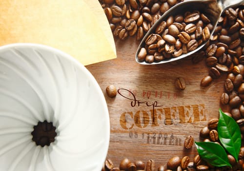 Portable plastic filter with coffee beans and a spoon surrounding the stamped text label on an old wooden coffee container for an interesting background